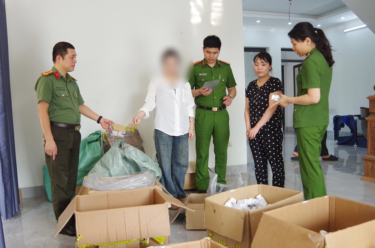 Hồ Thị Hoa (&aacute;o đen) v&agrave; h&agrave;ng giả l&agrave; thuốc chữa bệnh bị thu giữ.