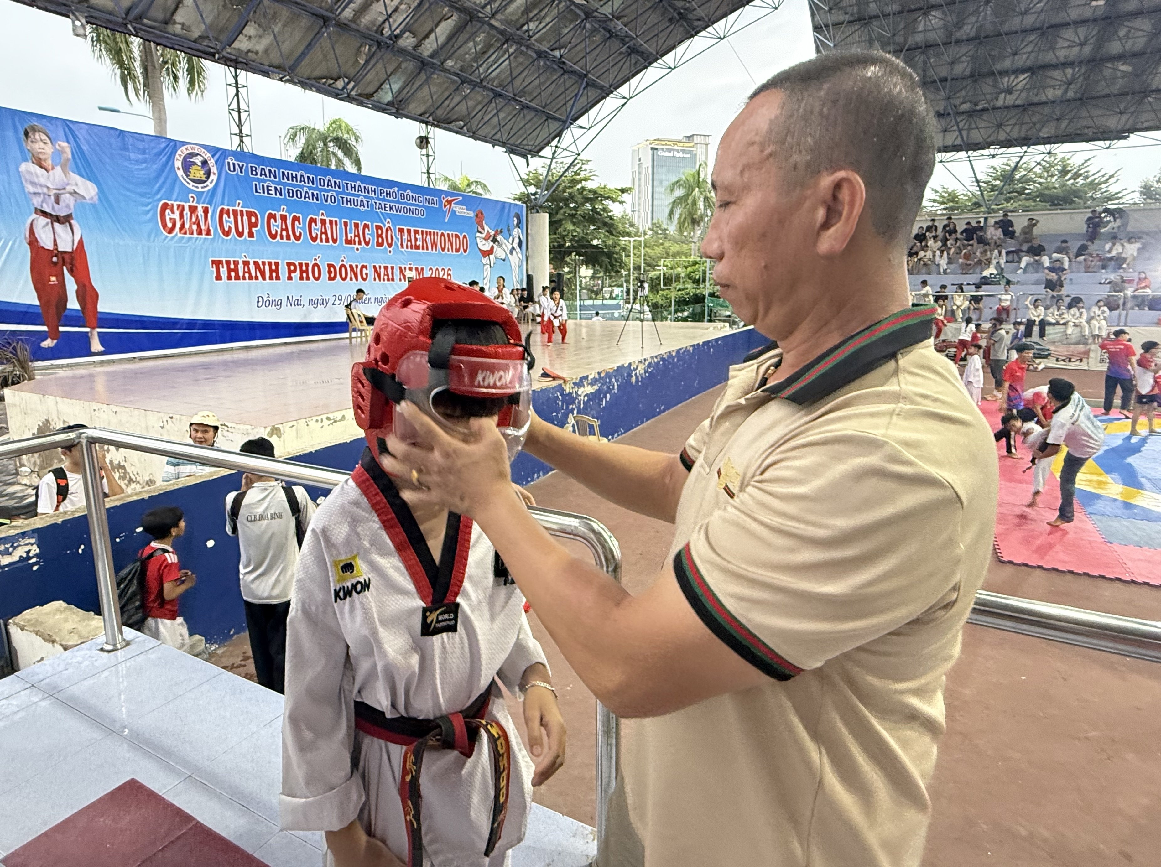 Huấn luyện viên Trần Công Minh chỉnh mũ bảo hộ cho học trò trước giờ thi đấu. Ảnh: VT Huấn luyện viên Trần Công Minh chỉnh mũ bảo hộ cho học trò trước giờ thi đấu. Ảnh: VT