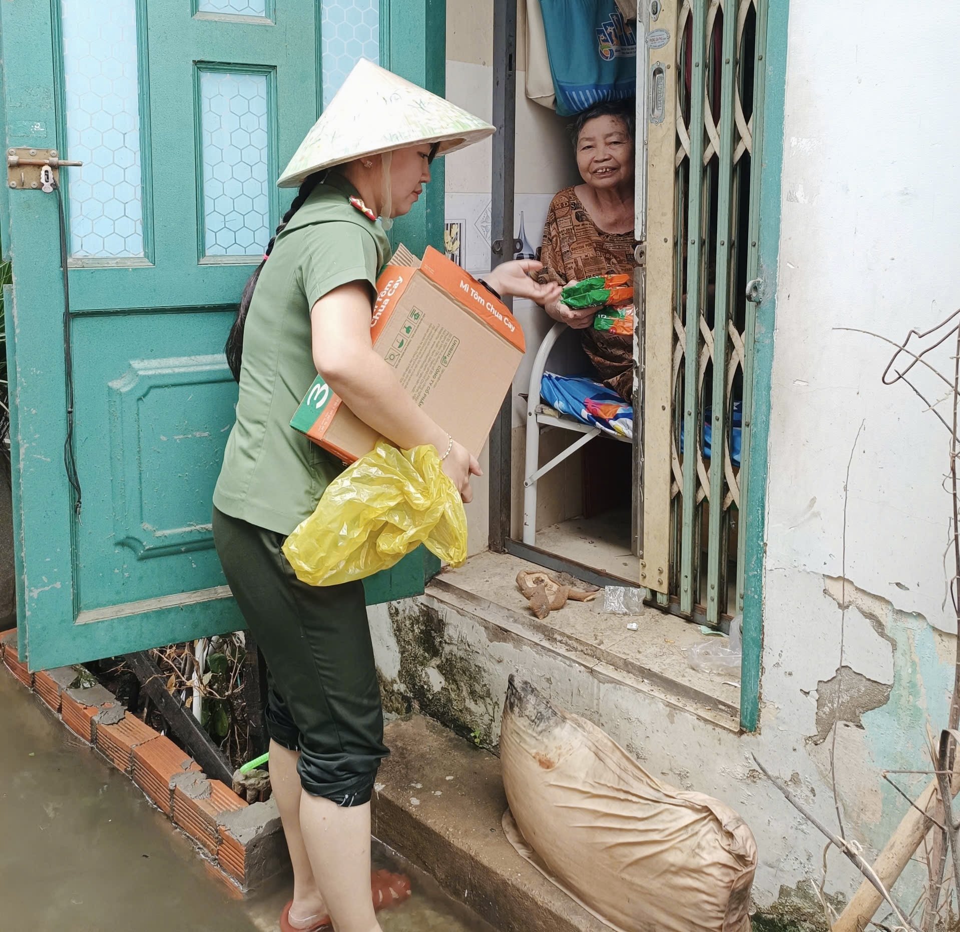 Đại u&yacute; Nguyễn Thị Hồng Đ&agrave;o, c&aacute;n bộ C&ocirc;ng an phường Hiệp B&igrave;nh, TP.HCM, hỗ trợ nhu yếu phẩm cho người d&acirc;n bị ảnh hưởng.