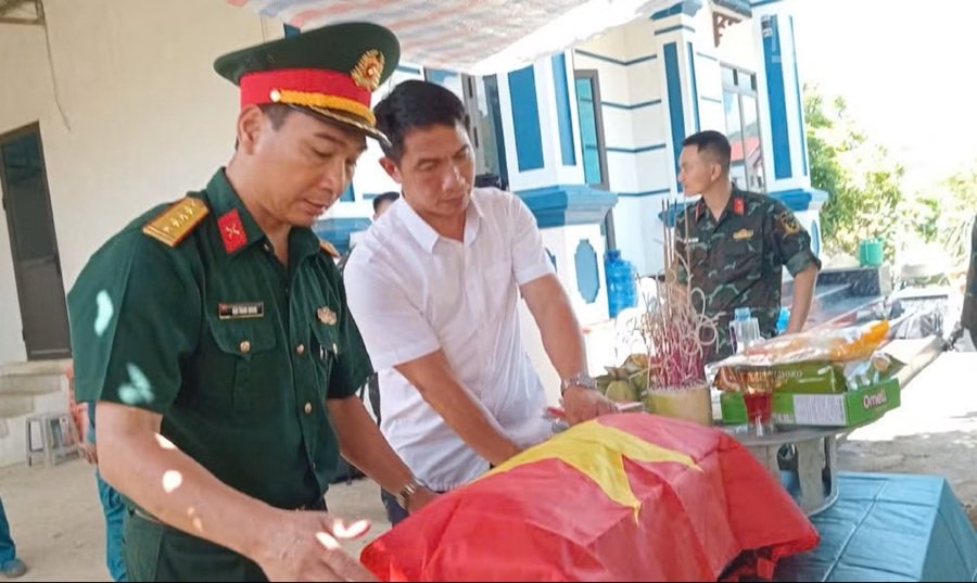 Thực hiện nghi thức phủ Quốc kỳ l&ecirc;n h&agrave;i cốt của c&aacute;c Anh h&ugrave;ng liệt sĩ được t&igrave;m thấy ở bản Cang Kiểng, x&atilde; Chiềng Khoong. (Ảnh: THỌ SƠN)