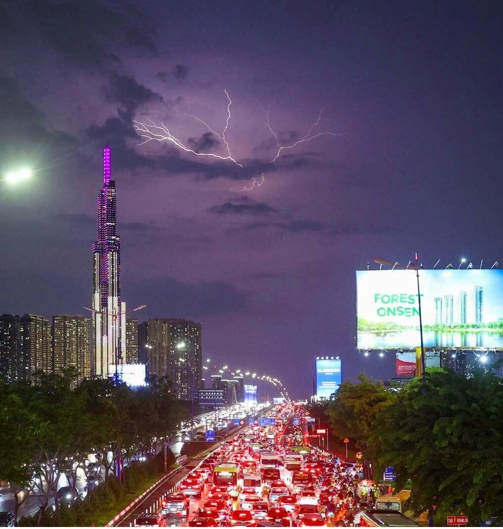 Tia s&eacute;t tr&ecirc;n bầu trời trung t&acirc;m TP HCM, b&ecirc;n tr&aacute;i l&agrave; t&ograve;a nh&agrave; Landmark 81 tầng, nh&igrave;n từ cầu bộ h&agrave;nh ga metro Thảo Điền, tối 1/10. Ảnh: Quỳnh Trần